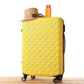 yellow four wheeled hard shell suitcase | Island Real Estate