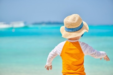 Child wearing rash guard at the beach | Island Real Estate