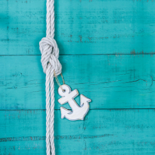 white rope know and small anchor on wood plank background