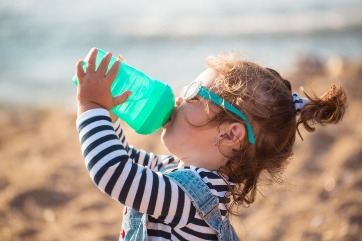 Toddler drinking water on the beach | Island Real Estate
