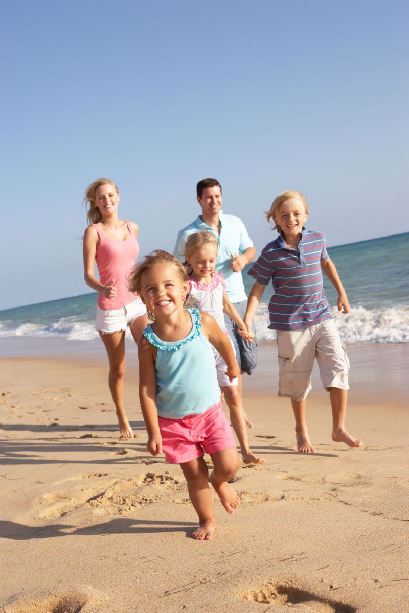family_beach | Island Real Estate parents running on the beach with their three young children